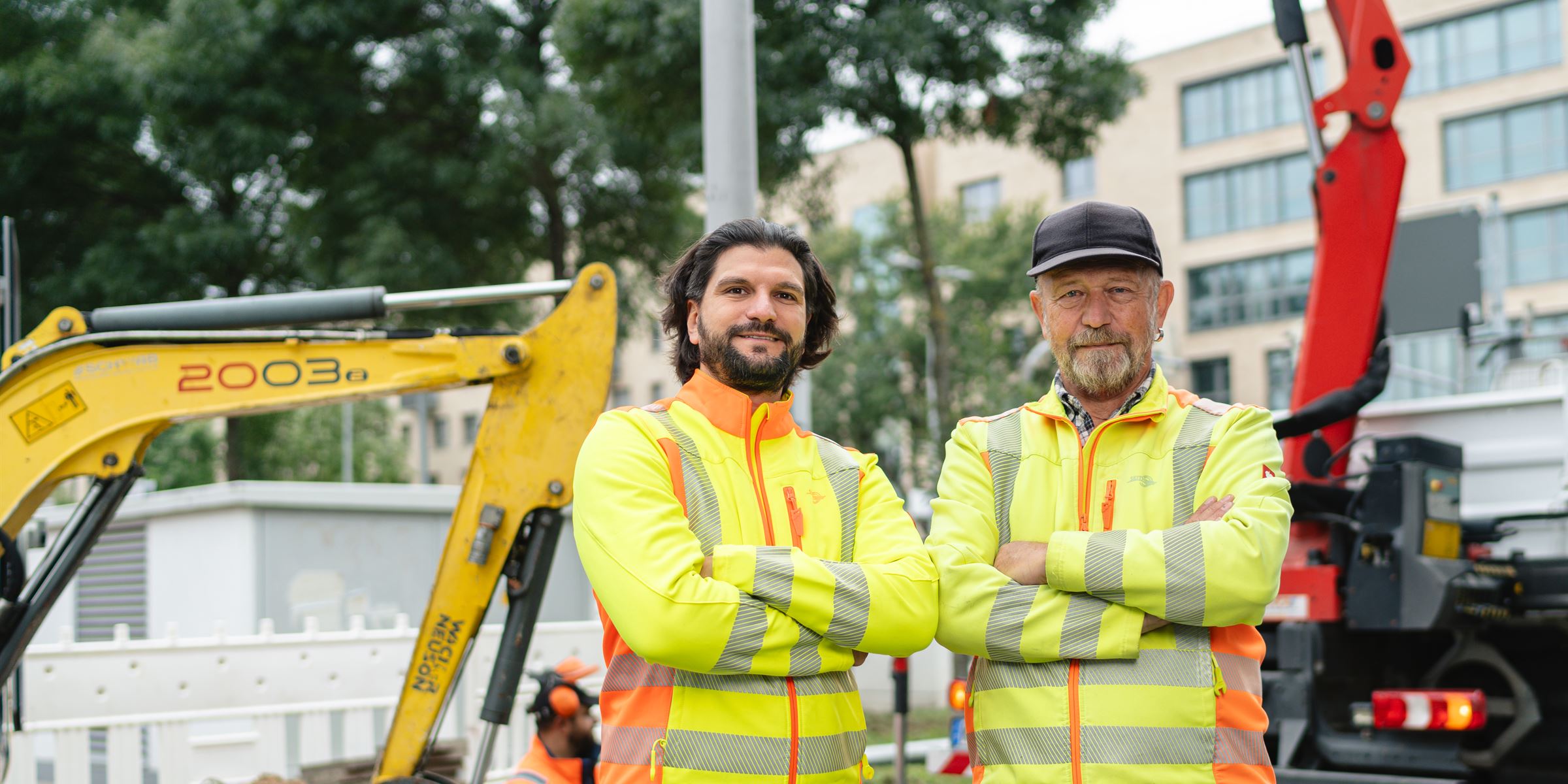 Zwei Mitarbeiter von Seith Energietechnik in Warnschutzkleidung vor Bagger und Kranwagen auf einer Tiefbaustelle in der Region Karlsruhe